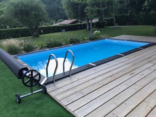 Photographie d'une piscine enterrée dans un jardin avec une terasse en bois